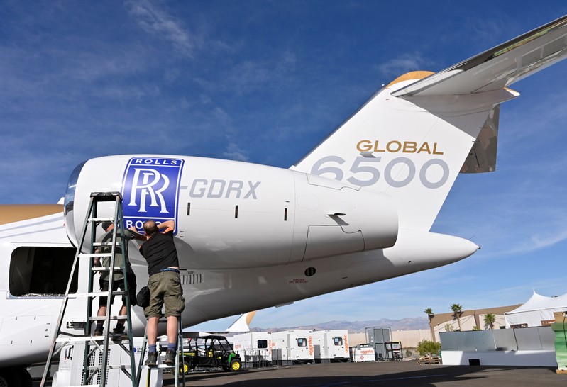 Workers apply a Rolls Royce decal to the engine of a Bombardier Global 6500 business jet at the