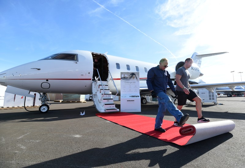 Workers roll out the red carpet for a Challenger 650 business jet at the Bombardier booth at