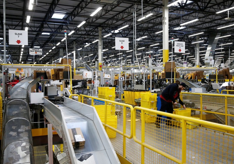 An employee monitors packages at automated scanning and labeling conveyor lines at the Amazon