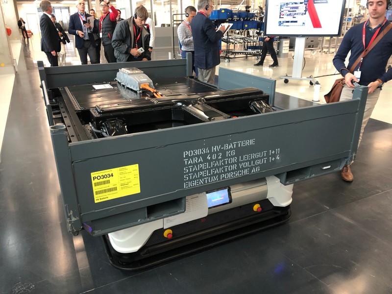 An electric battery pack is being carried to meet a car body at Porsche's Zuffenhausen