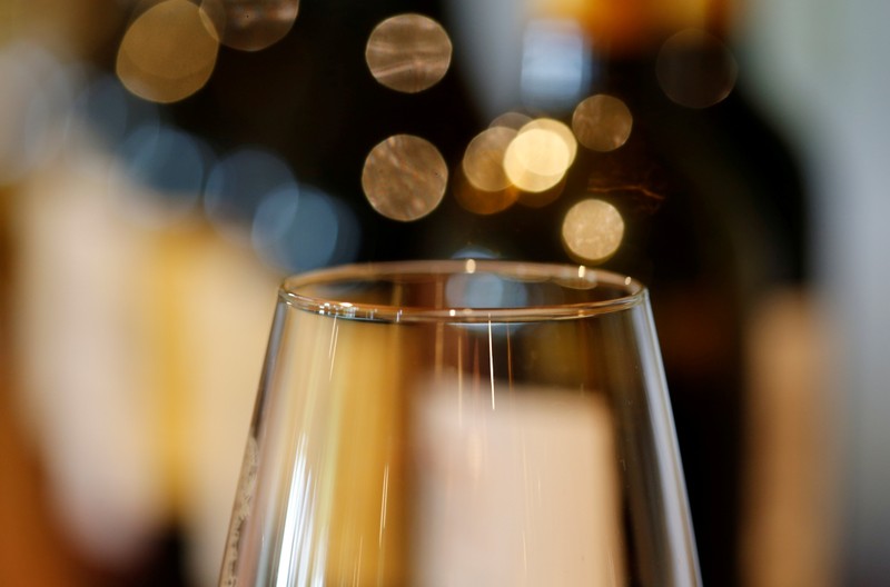 FILE PHOTO: A glass is displayed in front of bottles of French red wine at the Chateau du