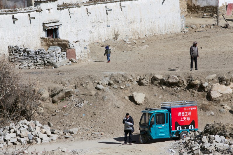 FILE PHOTO: Delivery man of Alibaba's logistics unit Cainiao talks on a phone as he delivers a