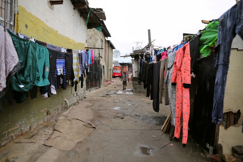 FILE PHOTO: A child walks past washing in Alexandra township in Johannesburg