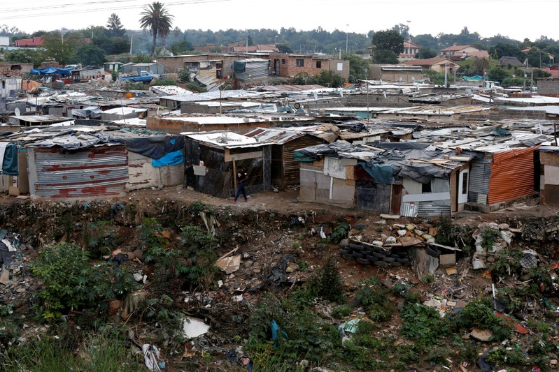 FILE PHOTO: Man walks between shacks in Alexandra township