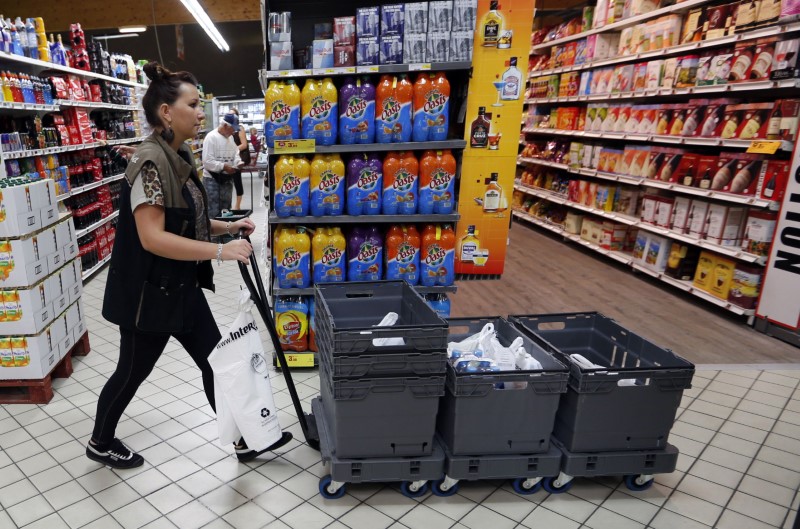 An employee pushes a caddy as she collects groceries at an Intermarche supermarket in Lanton