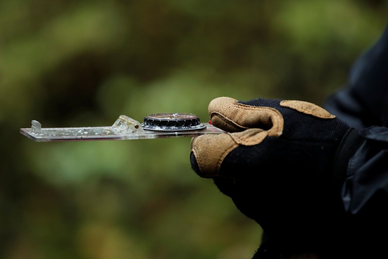 A volunteer uses a compass during a scour of an uninhabited wood at the call of the France's