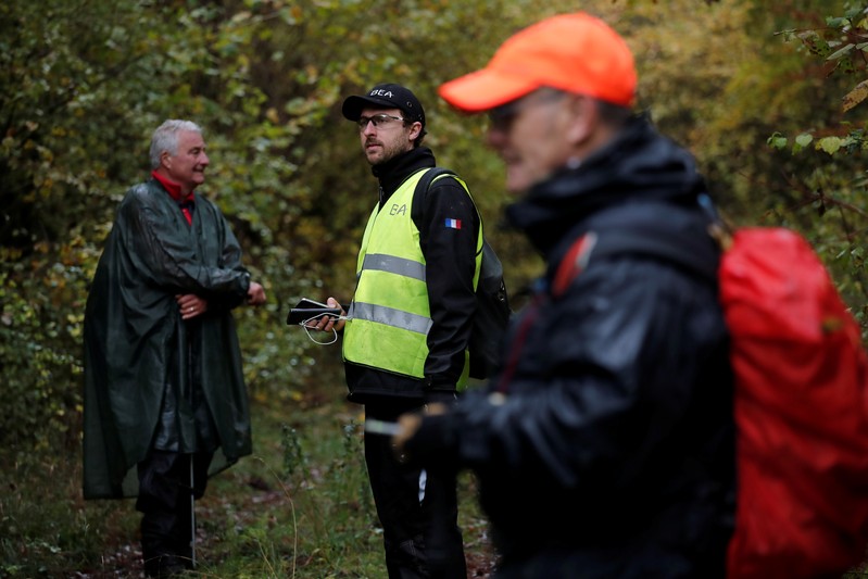 A member of the France's BEA aviation safety agency and volunteers scour an uninhabited wood to