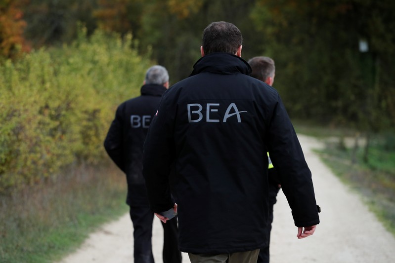 Members of the France's BEA aviation safety agency scour an uninhabited wood to find pieces of