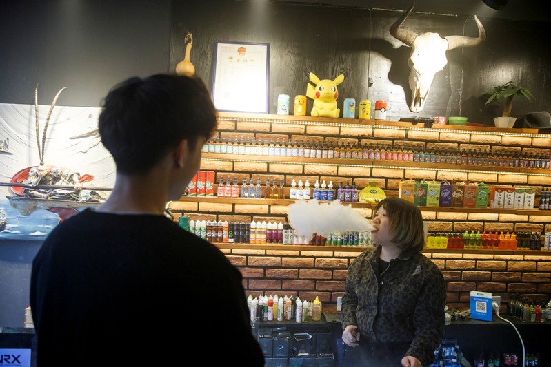 FILE PHOTO: Saleswoman exhales at Vape Shop in Beijing