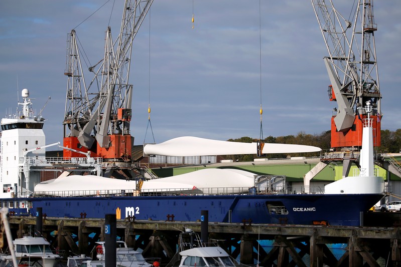 Cranes unload wind turbine blades from a ship in the port of Dieppe,