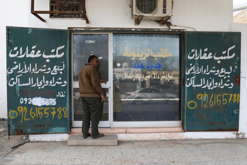 A man walks next to a real estate office in Tripoli