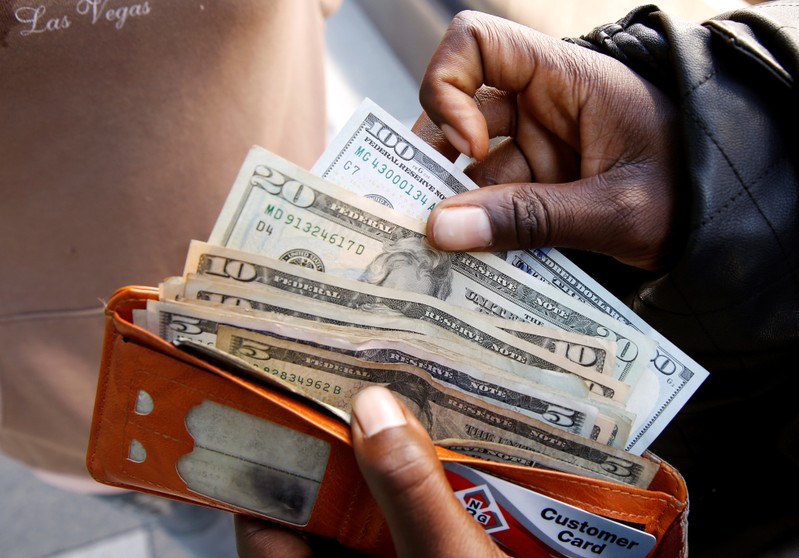 A man displays US dollar notes after withdrawing cash from a bank in Harare