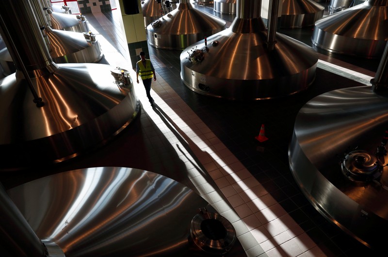 A worker walks near beer fermentation vats at Anheuser-Busch InBev brewery in Leuven