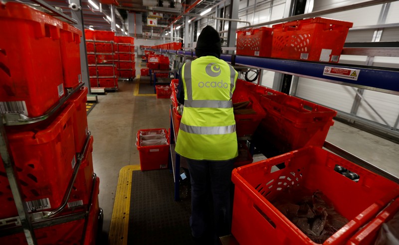 FILE PHOTO: A worker cleans returned shopping baskets at the Ocado CFC (Customer Fulfilment