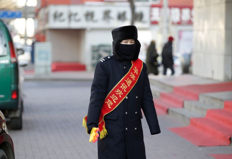 A sales assistant waits for customers outside a shop on a cold winter day in Harbin