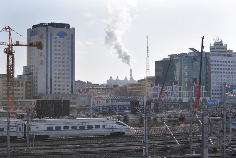 A train drives into Harbin railway station as smoke is seen from the chimney of a heating