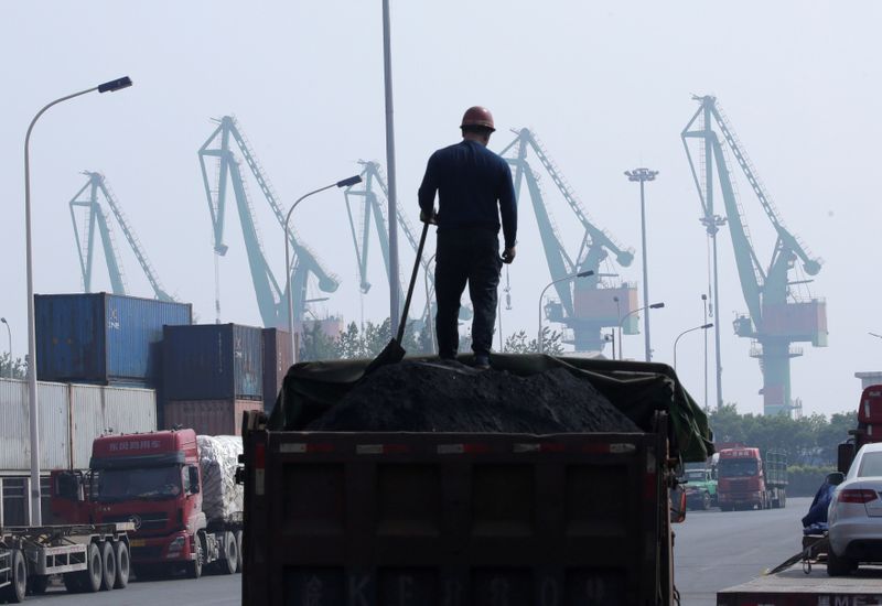 FILE PHOTO: A labourer loads coal in a truck next to containers outside a logistics center near