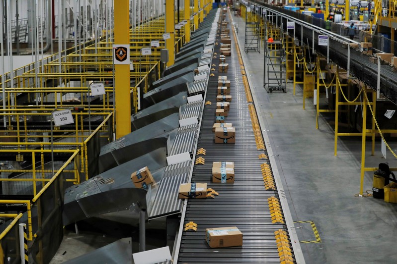 Amazon packages are pushed onto ramps leading to delivery trucks by a robotic system as they