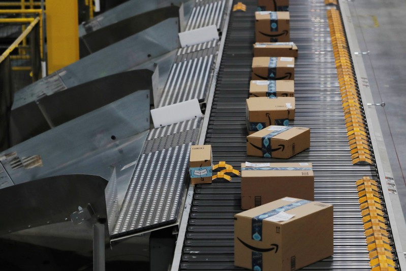Amazon packages are pushed onto ramps leading to delivery trucks by a robotic system as they