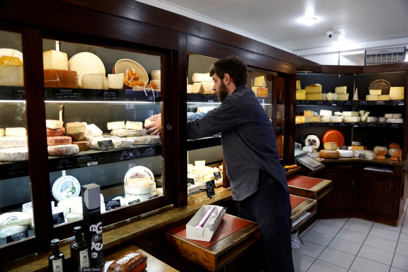 FILE PHOTO: A cheesemonger removes cheese at Beaufils affineur in Paris