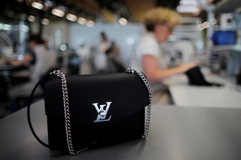 FILE PHOTO: The logo of Louis Vuitton is seen on a handbag as an employee works in a Vuitton