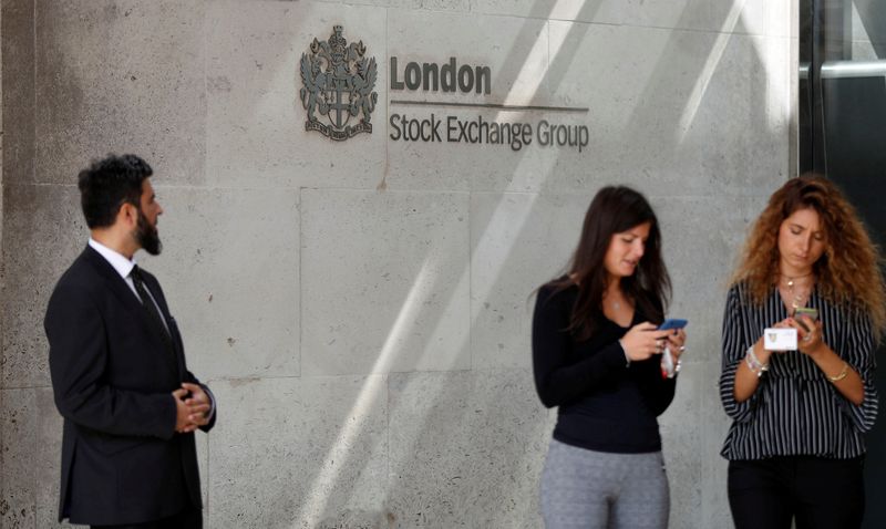 FILE PHOTO: People check their mobile phones as they stand outside the entrance of the London