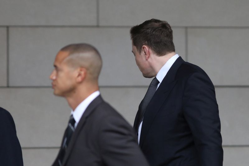 Elon Musk walks with his face turned away from cameras as he arrives at court for trial in Los