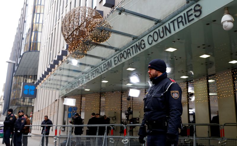 Journalists and police officers stand outside the Organisation of the Petroleum Exporting