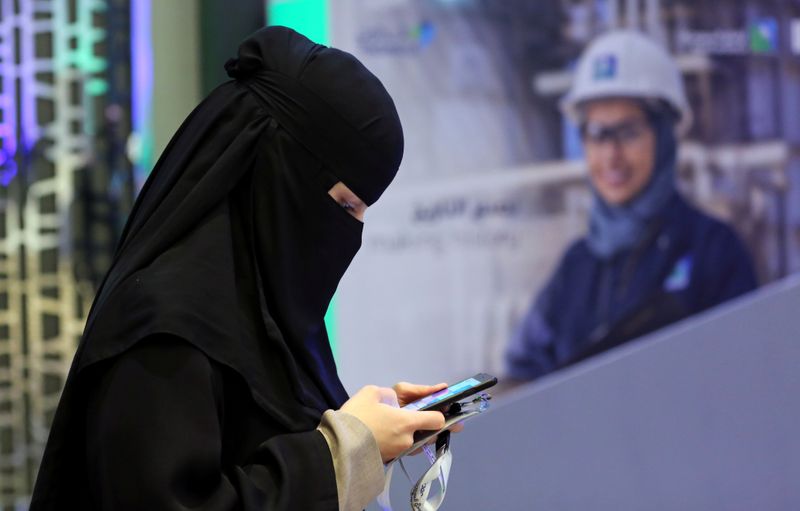 Participant uses her smartphone during the official ceremony marking the debut of Saudi