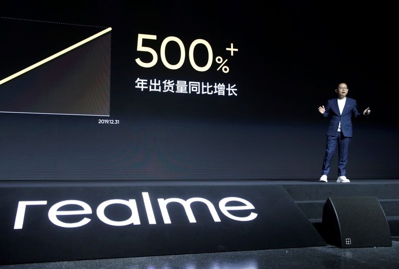 Man looks at mobile phone next to Realme logo during product launch event of X50 5G in Beijing