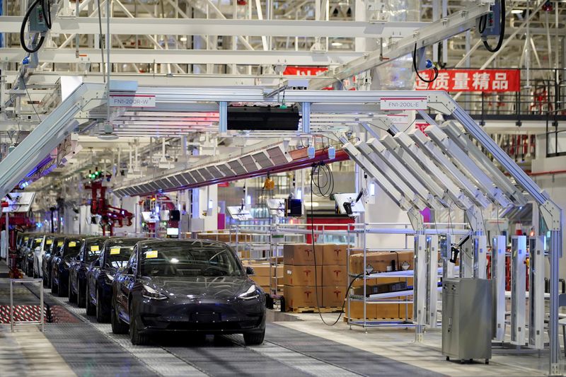 Tesla Inc CEO Elon Musk poses with Tesla China-made Model 3 vehicles owners onstage during a