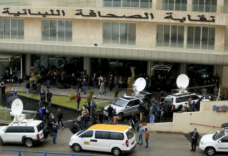 A journalist carries a camera near a car outside the house believed to belong to former Nissan