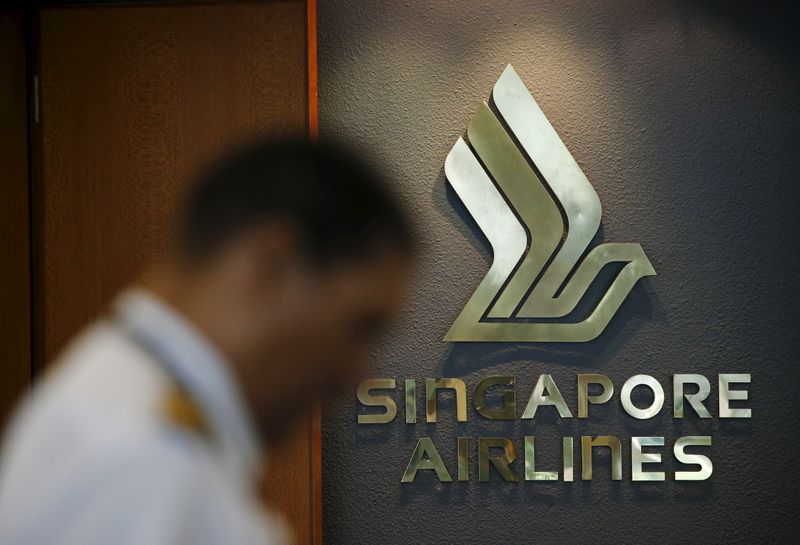 A flight crew passes a Singapore Airlines logo at Singapore's Changi Airport