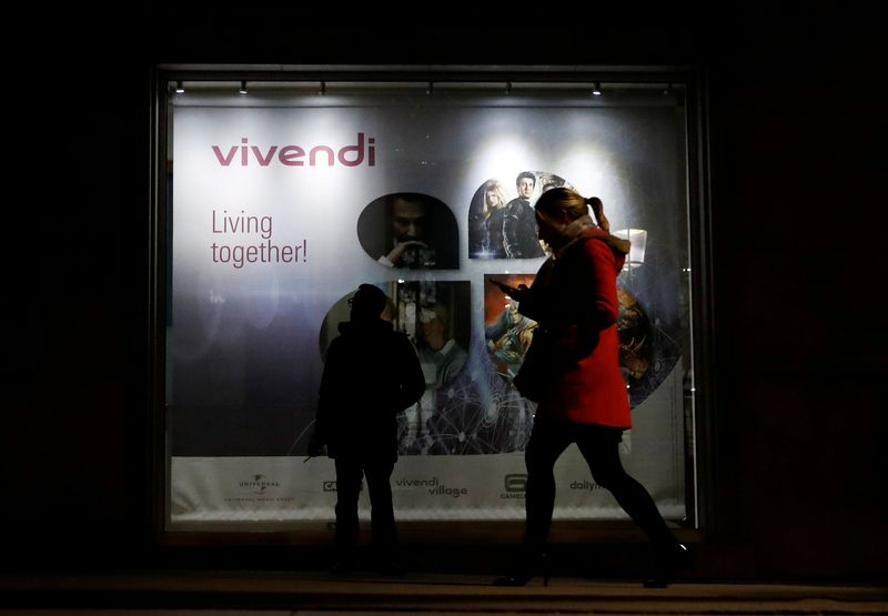 FILE PHOTO: A man stands as a woman walks past a sign of Vivendi at the main entrance of the