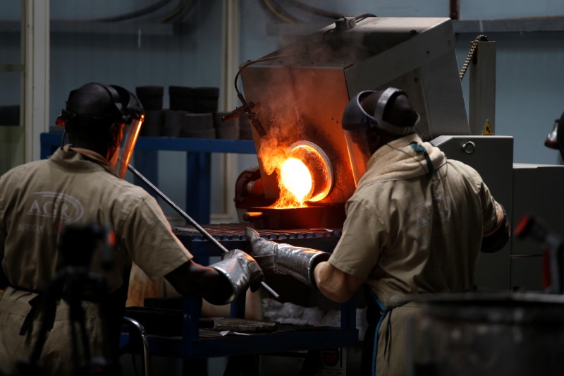 An employee pours liquid gold into a mould for the production of an ingot during the refining