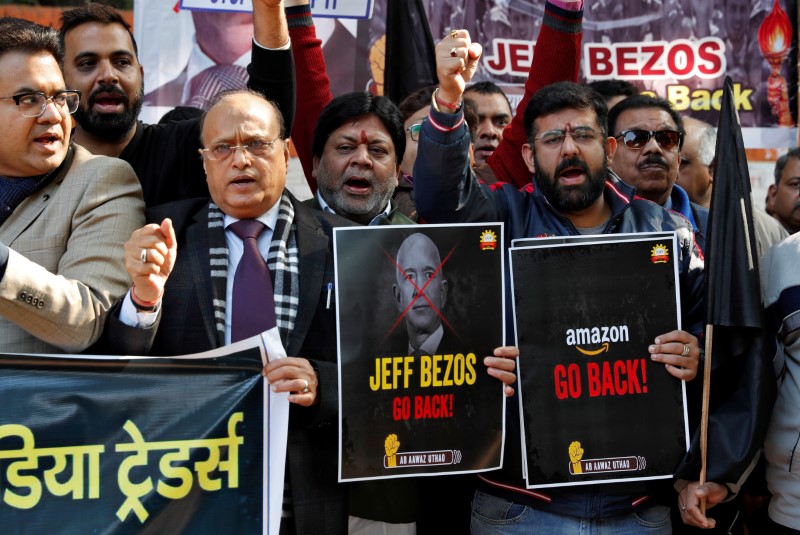 Members of the Confederation of All India Traders hold placards during a protest against the