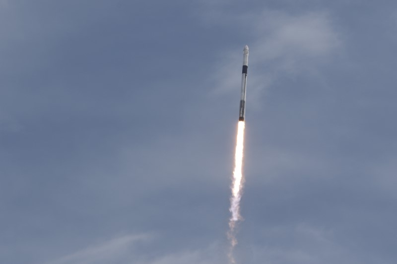 A SpaceX Falcon 9 rocket, carrying the Crew Dragon astronaut capsule, lifts off on an in-flight