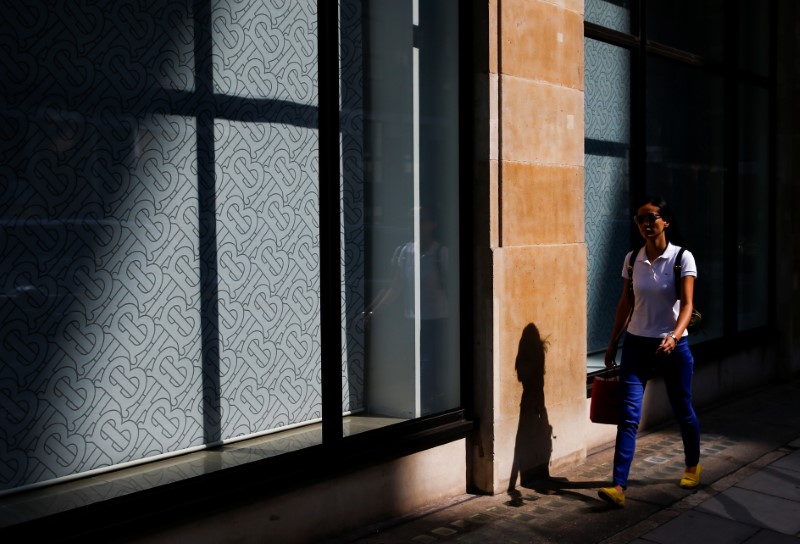 FILE PHOTO: The Burberry logo is pictured at a window as a woman walks past a Burberry office