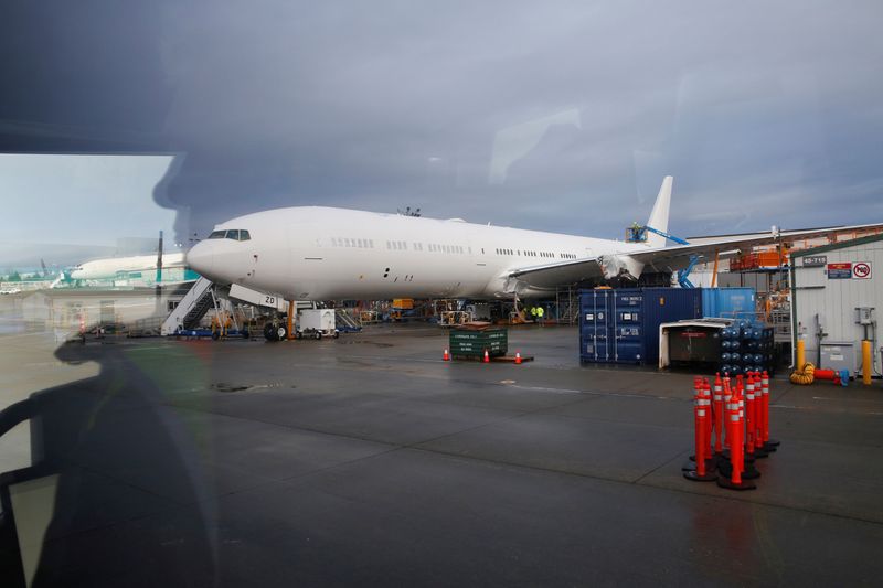 Boeing employees walk near a partially finished Boeing 777X airplane at the company's plant in