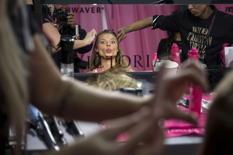 FILE PHOTO: A model sticks her tongue out as she gets her hair done backstage before the