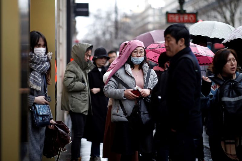 Tourist wears a protective mask at a duty free shop in Paris as the country is hit by the new