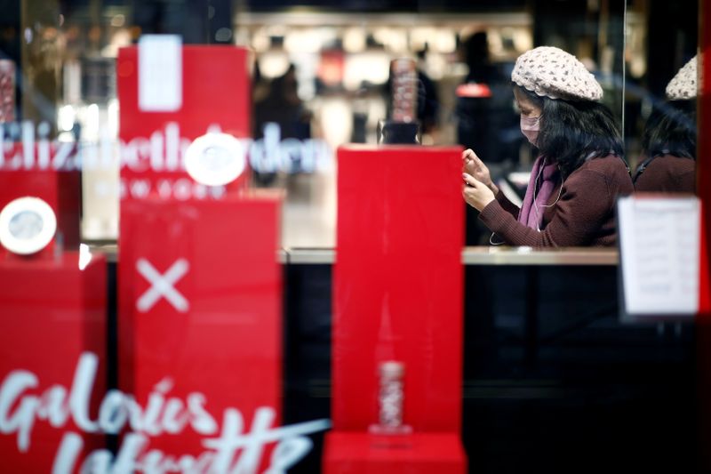 Tourist wears a protective mask as she looks at her mobile phone at the Galeries Lafayette