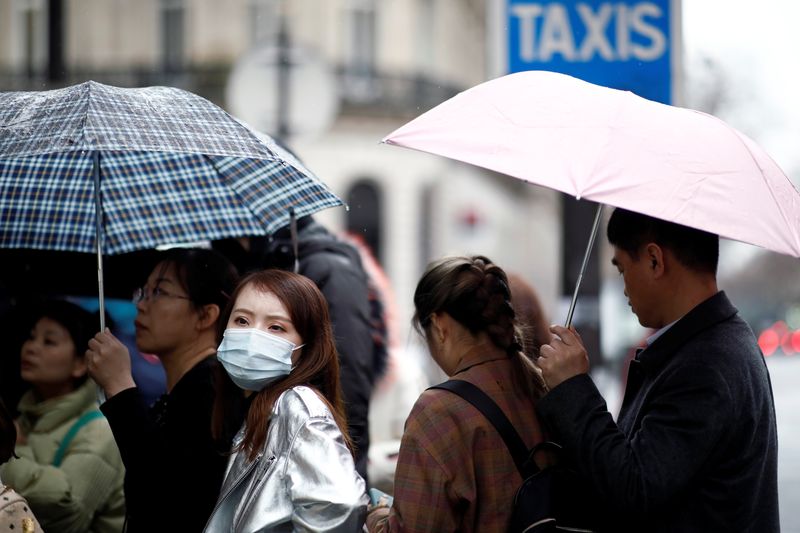 Tourist wearing protective masks enter a duty free shop in Paris as the country is hit by the