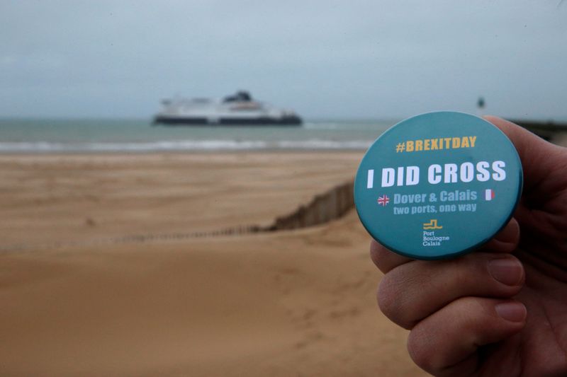 A man poses holding a badge made by the port of Boulogne Calais to mark Brexit day as P&O