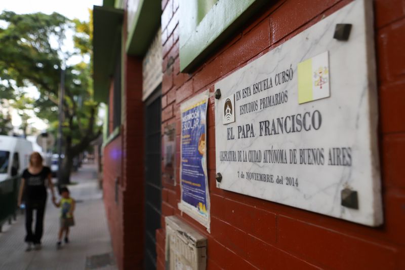 A woman and a child walk near a school where Pope Francis attended primary school when he grew