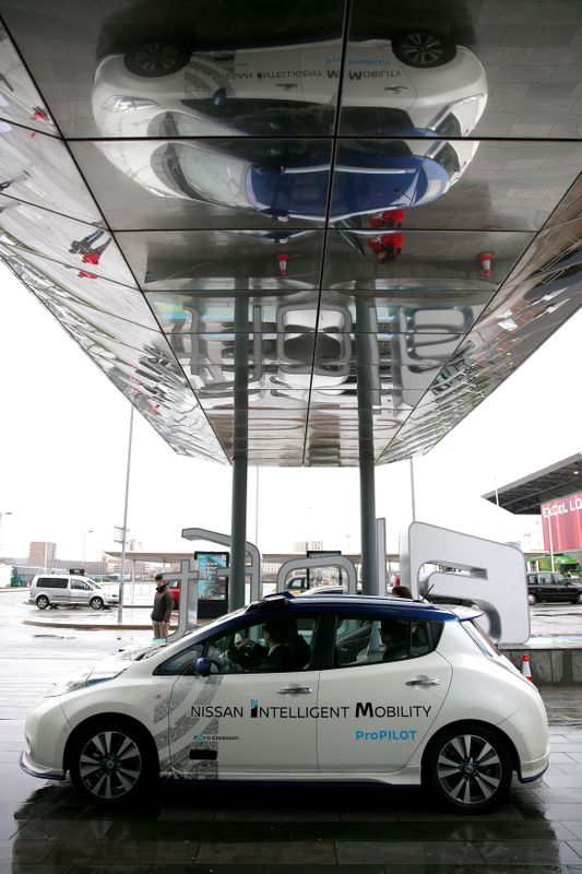 FILE PHOTO: A modified Nissan Leaf, driverless car, is reflected in an awning during a pause