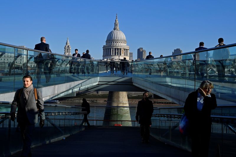 Workers are seen crossing the Millennium Bridge, with St Paul's Cathedral seen behind during
