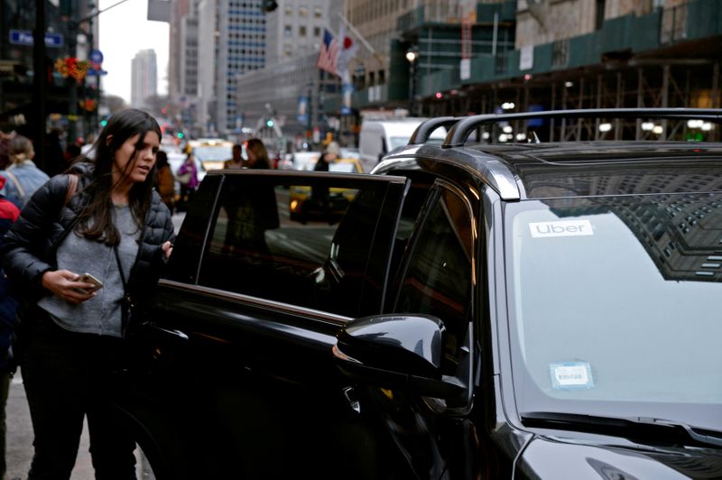 The Uber Lyft and Juno logos are seen on a car as it drive up 6th Avenue in New York City