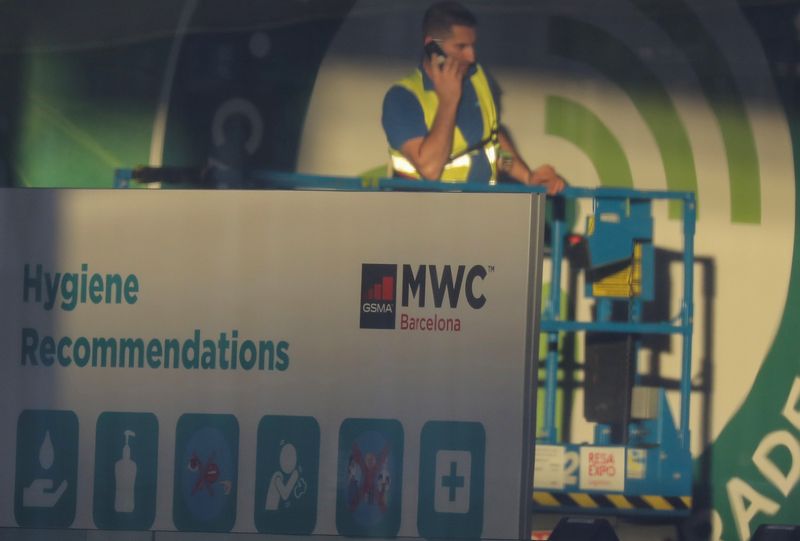 Employee is pictured next to a banner with information of MWC20 (Mobile World Congress) in