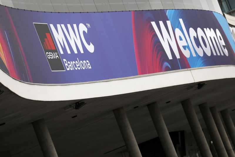 Employee is pictured next to a banner with information of MWC20 (Mobile World Congress) in